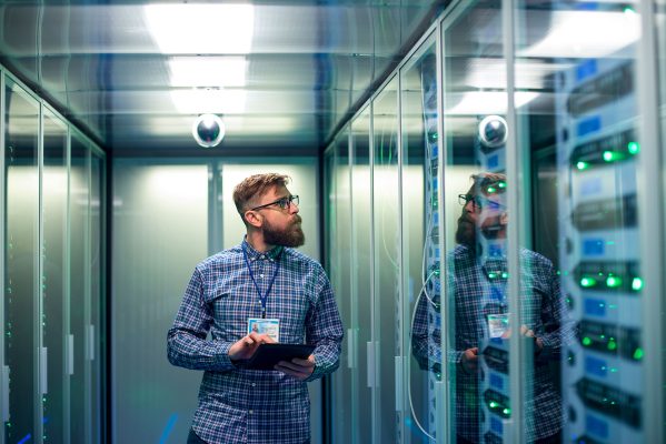 Professional with tablet inspecting active data center servers